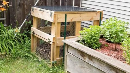 Wooden compost bin setup in the corner of a garden